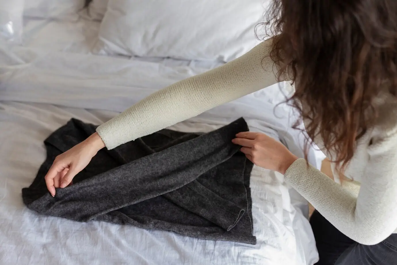 Nahaufnahme einer Frau, die Kleidung zusammenlegt.